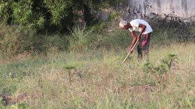 Close-up footage of An Indian farmer digging the ground with the help of a shovel in the field, india