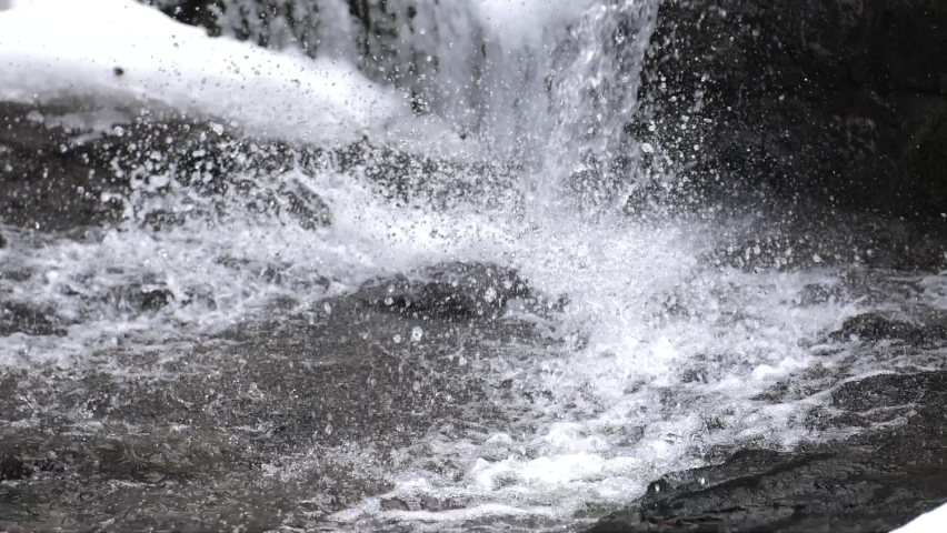 Low angle view of a water stream crashing down on the rocks in slow motion