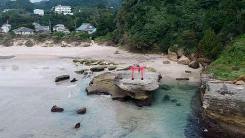 White Sand Beach Of Shirahama With Red Torii Gate On The Rock. Izu Peninsula In Japan. aerial drone pullback