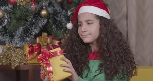 Brazilian girl, curly hair, christmas clothes. questioning what is inside the present, doubt and anxiety. Christmas, Merry Christmas. 4K 60fps Premium cinematic video