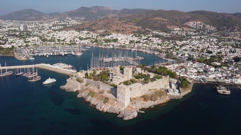 Aerial view of Bodrum Castle and Bodrum Marina in Turkey. Drone flying over the sea. The port city is visible on mountains background. Bodrum is a popular tourist destination in the Turkish Riviera.