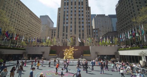 New York, New York United States - April 23,  2022: Flipper's Roller Boogie Palace at The Rink in Rockefeller Center. Pan down from the top of 30 Rock to full shot of roller skaters on the rink