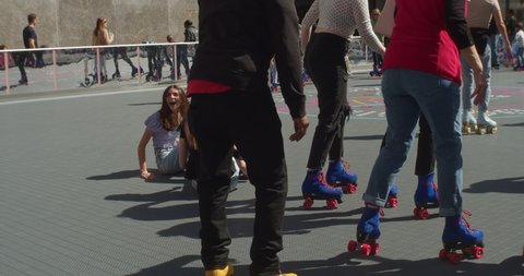 New York, New York United States - April 23,  2022: Flipper's Roller Boogie Palace at The Rink in Rockefeller Center. Young girl laughing after falling on roller skates. Daytime.