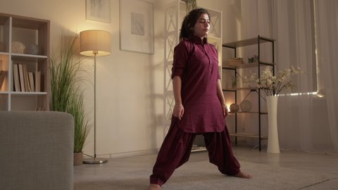 Yoga stretching. Healthy activity. Training at home. Motivated woman practicing leg split virabhadrasana warrior pose at home living room.