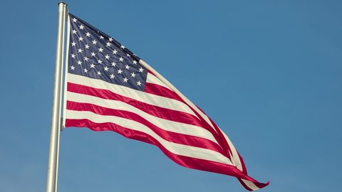 American flag of the United States of America waving against blue sky, slow motion from 120 fps