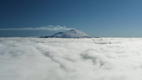 Aerial shot with drone of Etna above the clouds at dawn. Low clouds with a view of the Etna volcano in Sicily above the clouds. Etna in winter. Sicily in winter. Etna seen from the Nebrodi above Lake.