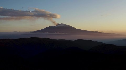 Aerial shot with drone of Etna above the clouds at dawn. Low clouds with a view of the Etna volcano in Sicily above the clouds. Etna in winter. Sicily in winter. Etna seen from the Nebrodi above Lake.