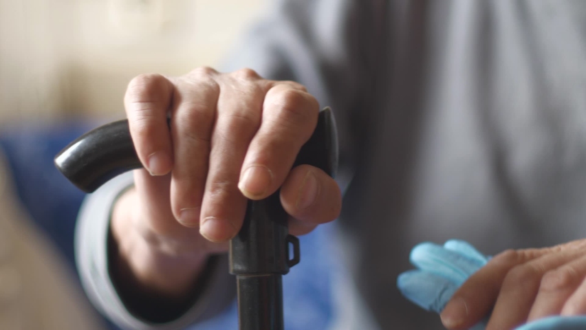 Close-up Patient with walking stick, medic in gloves shakes hands, support after illness. Care in a nursing home. The doctor encourages the patient and wishes recovery. selective focus Royalty-Free Stock Footage #1089599679