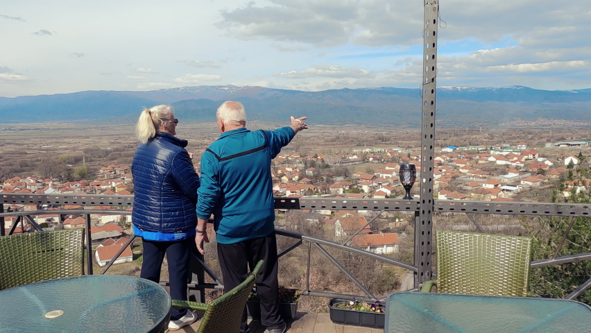 Senior romantic hike couple navigate route from high viewpoint, slow motion