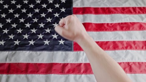 rised caucasian fist on blurry US flag background