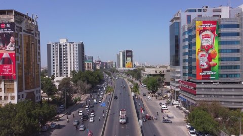Beautiful day shot from a drone of one of Karachi's busiest roads, surrounded by commercial glass towers high-rises and billboards. Karachi, Pakistan. 25th March 2021