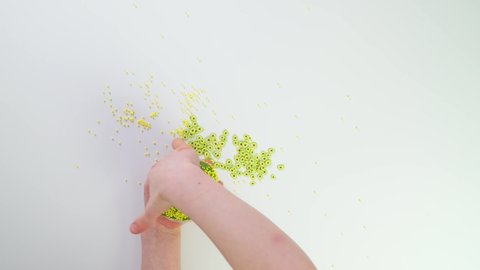 Top view child playing with slime. Children hands stretch slime and connect avocado toppings. Pour balls into slime. Cutting green slime with scissors on white table. Creative game on white background