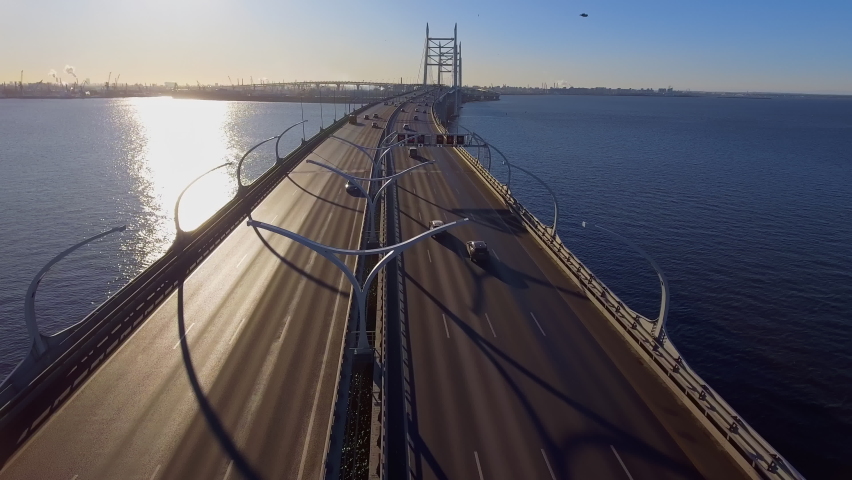 Drone span over high-speed road towards the new cable-stayed bridge in the early morning, northwest high-speed diameter, bypass road, green lawns on the edges of the highway, mounded islands