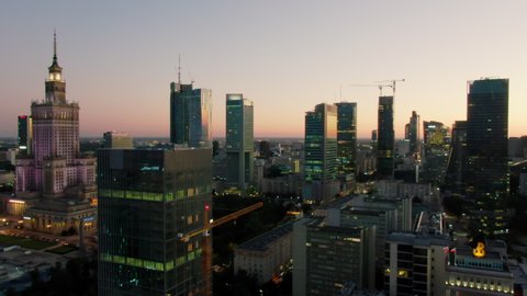 Warsaw, Poland - SEPTEMBER 2, 2021: Establishing Aerial Night view of Downtown District Skyline. Palace of Culture and Science, Skyscrapers with Office buildings as Urban Cityscape. Drone orbit shot