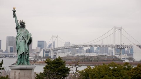 Tokyo, Japan - April 23, 22: Odaiba Statue of Liberty and Tokyo skyscrapers with Rainbow bridge in the background, Japan. High quality FullHD footage
