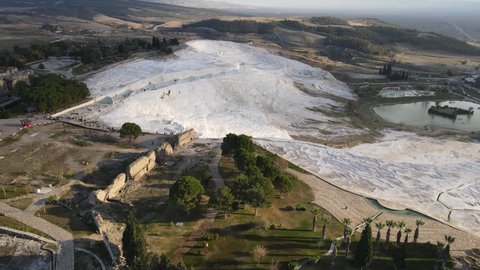 Drone view of Pamukkale travertines, natural beauty consisting of waterfalls and swimming pool with white minerals in Turkey, white travertines on one side of the mountain