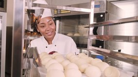 Professional African American female chef in white cook uniform, gloves, and apron making bread from pastry dough, preparing fresh bakery food, baking in oven at restaurant's stainless steel kitchen. - Powered by Shutterstock - Get 15% off with code: PIKWIZARD15