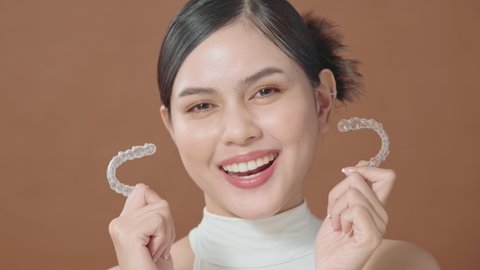 A young woman with beautiful teeth is holding Invisalign, healthy dental concept 