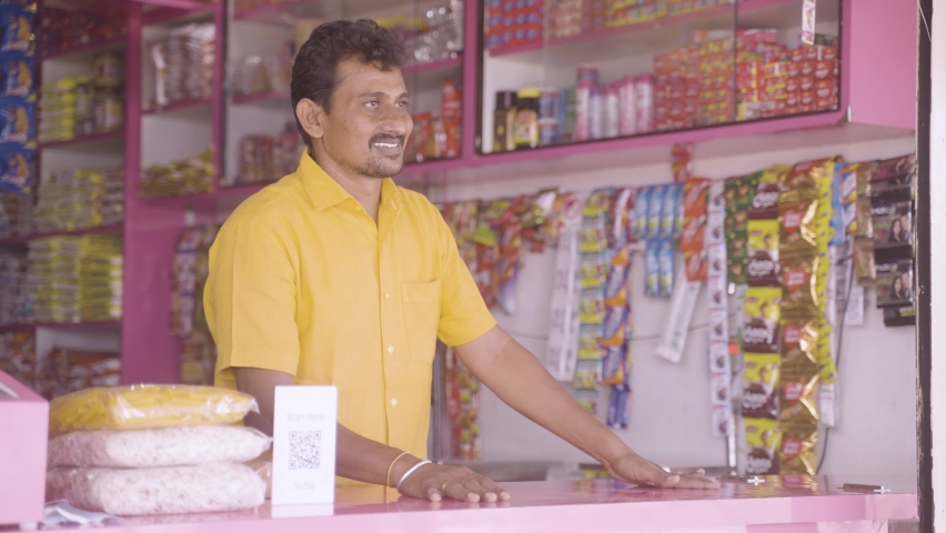 handheld shot of kirana or grocery merchant greeting customer at retail store - concept of successful business, communication, conversation.
