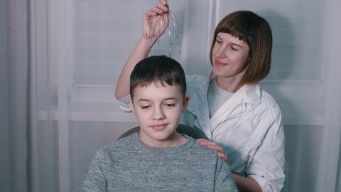 Masseuse Massages the Head of a Child with a Capillary Acupuncture Massager. Smiling laughing boy relaxing in a chair during the massage. Overwork, blood flow, feeling. Antistress, pleasure, help.