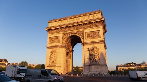 Paris France: Triumphal Arch of the Star (Arc de Triomphe de l'Étoile) - famous landmark and tourist attraction at sunrise. Traffic on the street in a sunny morning under clear blue sky. Apr 22.2022.