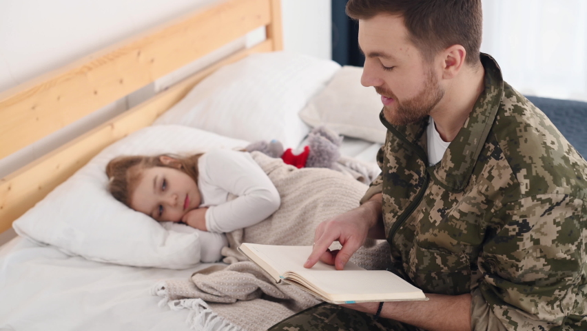 Dad reading the story. Soldier in uniform is at home with his little daughter.