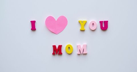 Phrase I Love You Mom from colorful wooden letters and a beating pink heart. Congratulations on mother's day. 4K looped stop motion animation