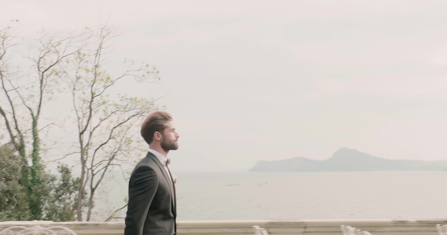 Young groom walks near luxury flower bouquets on wedding ceremony