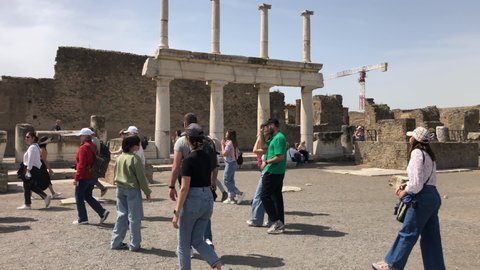 Pompeii, Naples - APR16, 2022: Pompeii guided tourists group tours in the ancient ruins sightseeing historic landmark of Pompeii, Italy. A lot of tourists explore the Ruins Of Pompeii.