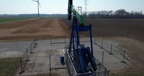 Wind turbine and an oil extraction pump on agricultural fields. A contrast in renewable and fossil fuels.