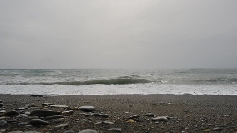 Waves on the sea pebble beach and cloudy sky