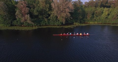 Cinematic drone shot on rowing boat. Sports canoe with a team of eight rowing through calm waters on the Dnieper River in Kyiv, Ukraine. rowing team training. Eight rowers in boat on River.