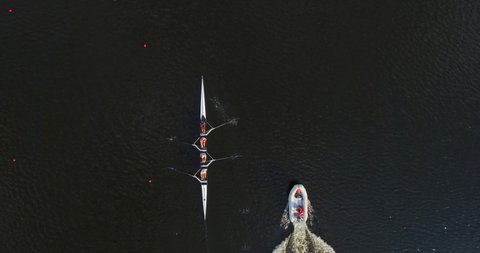 Top view on sports canoe and crew four Ukrainian athletes with coach in motor boat. Summer training team four athletes in rowing. Rowers are trained on the Dnieper River in the city of Kyiv, Ukraine.