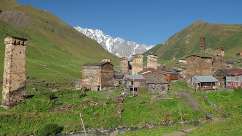 Beautiful panorama of the Ushguli village with Svan towers in Svaneti region in Georgia. Medieval stone tower houses with Caucasus Mountains at background. Slow panning