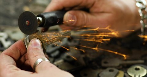 Locksmith in workshop makes new key, use grinding engraving machine, production of duplicate metal key.