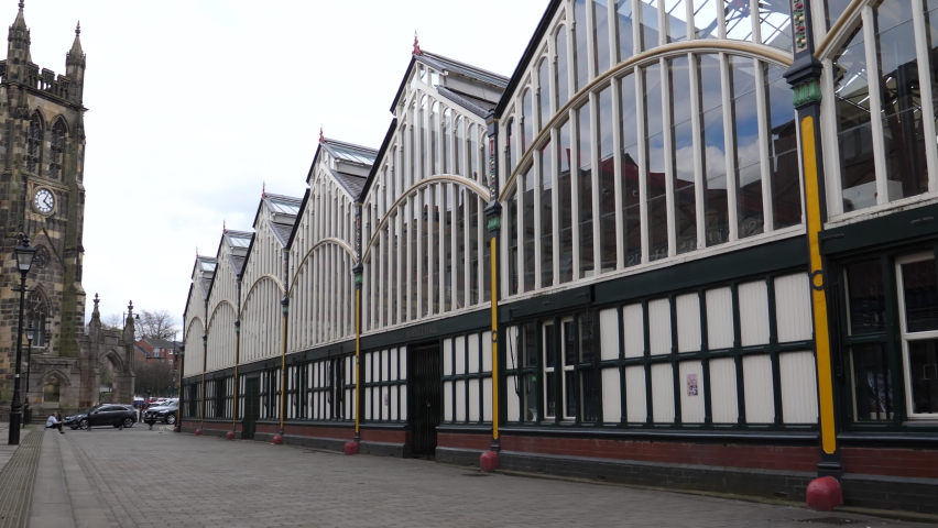Distant cars and people moving past old Market Hall building and St Mary church in Stockport downtown, United Kingdom.