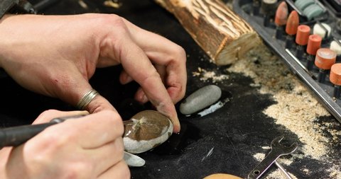 Close up male hands using power stone working tools graver, carving while crafting, Creating craft handmade souvenirs.