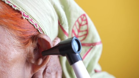  examining senior patient ear by otoscope close up 