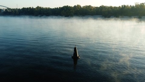 drone flies around a buoy on the river, morning mist over the water, fog
