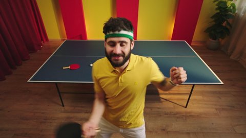 Funny and crazy ping pong player dancing excited in front of the camera after he win the ping pong game he play with the paddles and ball