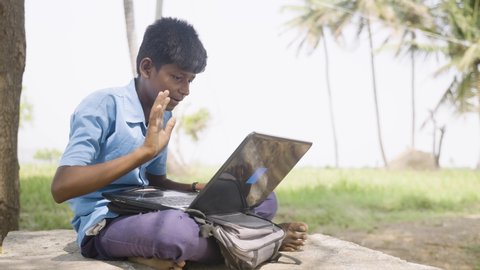 village school kid during online class using laptop near agriculture farmland - concept of education, distant e-learning and technology