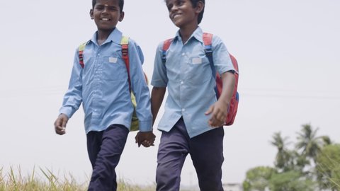 Village teenager kids in uniform by holding hands going to school on rural roads - concept of education, friendship and comminution