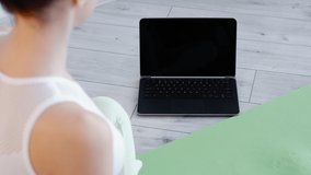 Online yoga class. Fitness lesson. Sport wellness. Unrecognizable woman watching pilates virtual course at laptop empty space blank screen at home.