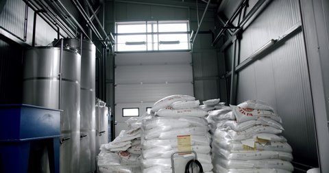 Production of beer with malt grains in the large mill in the brewery. Large beer grinder. Malt grains that are stored at the plant. Crushing malt. Malt bags.