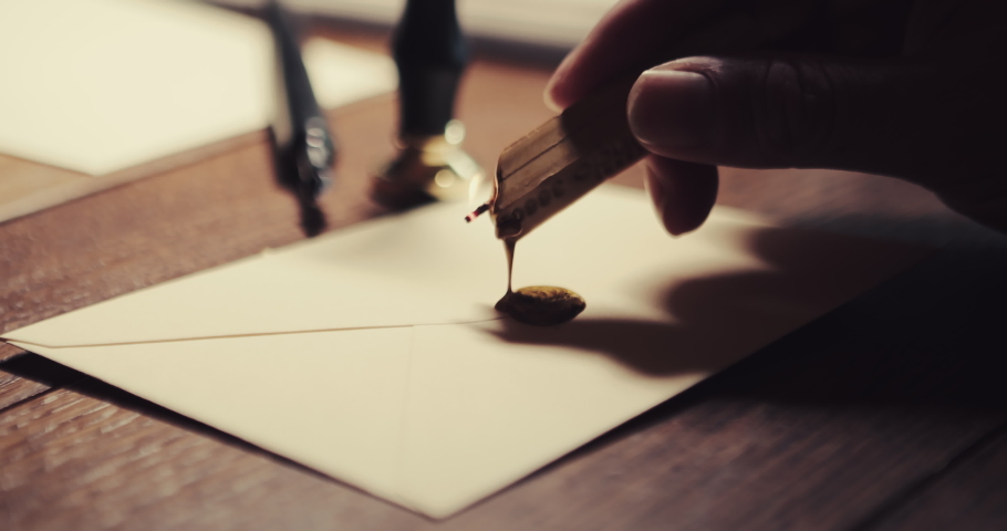 The caucasian hand carries the wax to the letter and then presses the wax seal into the hot wax to seal the letter. Close up shot - copy space | Shutterstock HD Video #1089633849