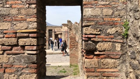 Pompeii, Naples - APR16, 2022: Pompeii tourists groups in the ancient ruins sightseeing historic landmark of Pompeii, Italy. A lot of tourists explore the Ruins Of Pompeii.