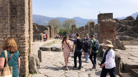 Pompeii, Naples - APR16, 2022: Pompeii tourists groups in the ancient ruins sightseeing historic landmark of Pompeii, Italy. A lot of tourists explore the Ruins Of Pompeii.