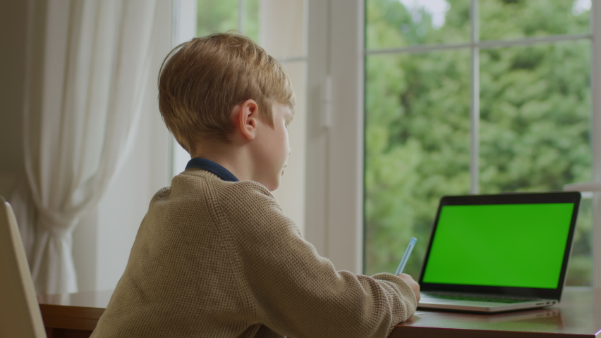 School boy using mobile phone and showing green screen at camera. Kid holding horizontal chroma key mobile phone screen.