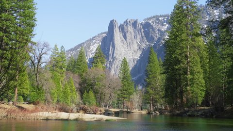 Cinematic Cathedral Rocks in Yosemite valley National park reflecting in Merced River. Scenic peaks surrounded by green pine forest on sunny summer day, Travel adventure concept