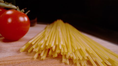 SUPER SLOW MOTION, CLOSE UP, PROBE LENS: Detailed overview of spaghetti lying on wooden surface in slow motion. Italian pasta close up. Raw pasta on countertop shot with probe lens and cinema robot.